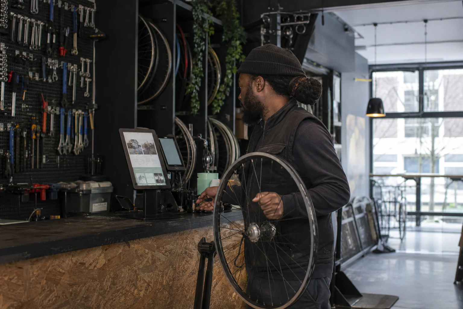 Black entrepreneur testing his redesigned site on a tablet in his bicycle repair shop