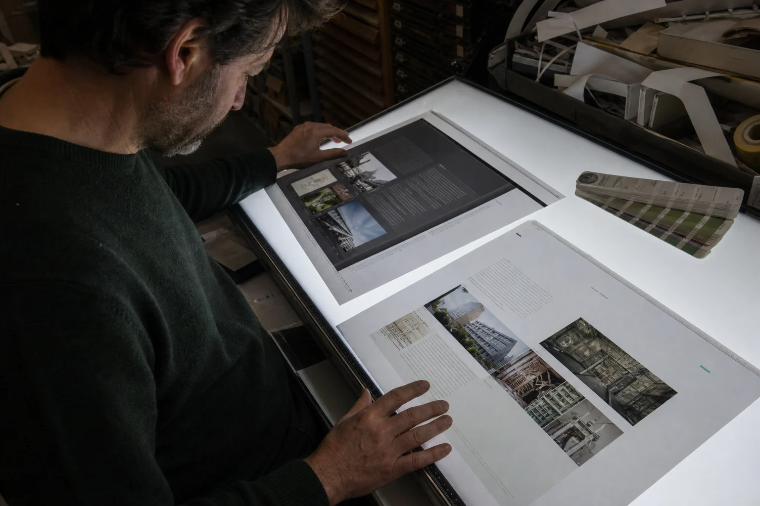 Designer comparing old and new printed website pages on a light table